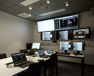 Samarbejdet foregår via videokonference. En Crestron-matrix sørger for at indholdet fra mødet bliver delt på kryds og tværs af skærmene og sender samtidig også indholdet til videokonferencens øvrige deltagere.